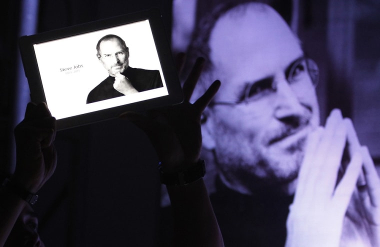 Image: A man holds an iPad displaying a photo of Steve Jobs during a 'Steve Jobs Day